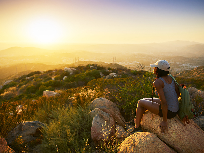 rear view of woman hiker sitting on rock